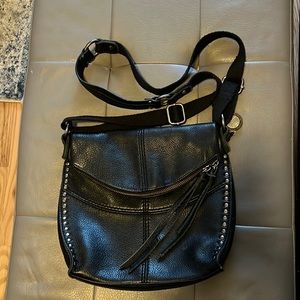 Black leather purse, shoulder strap is canvas.  Front decorative metal design